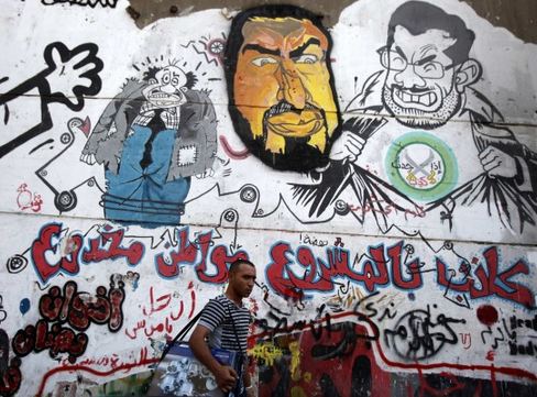 Amr Abdallah Dalsh/Reuters -  A man walks past graffiti depicting ousted Egyptian President Mohamed Morsi and others in downtown Cairo on Sept. 24.